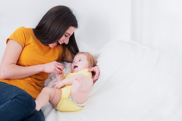 Foto mãe, brincando na cama com bebê