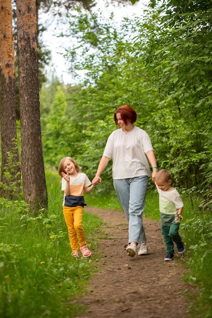 mãe caminha com dois filhos no verão na floresta