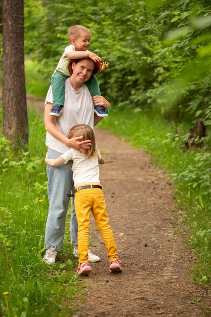 mãe caminha com dois filhos no verão na floresta