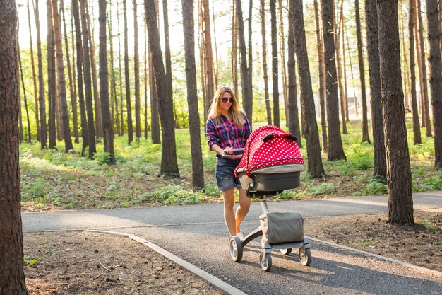 Mãe caminhando enquanto empurra um carrinho de bebê no parque.