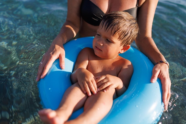 Mãe carinhosa monta seu filho em um anel inflável no mar