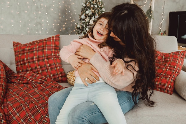 Mãe carinhosa, rindo, abraçando filha criança fofa sorridente, família feliz, se divertindo brincando, sentindo alegria, abraçando