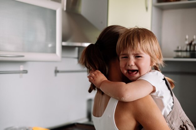 Mãe carregando filha chorando em casa