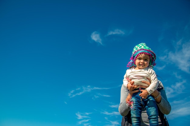 Mãe carregando filha contra o céu azul