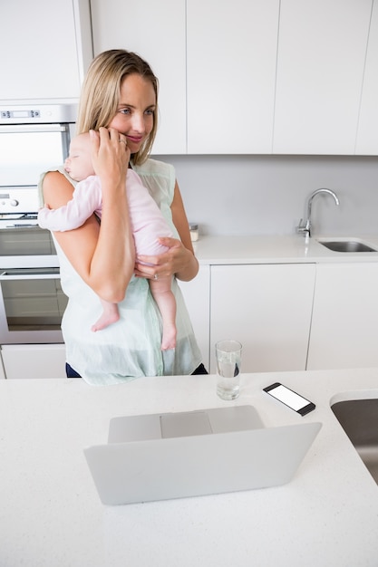 Mãe carregando seu bebê na cozinha