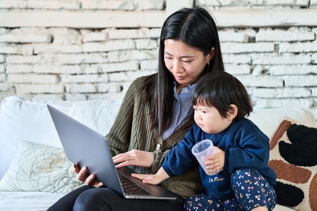 Mãe chinesa e bebê sorrindo na tela do laptop tempo alegre