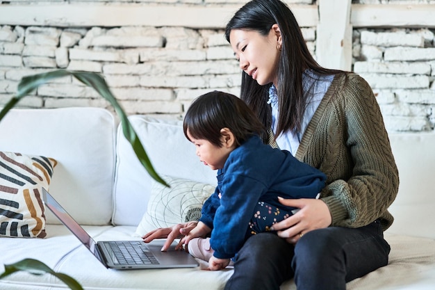 Mãe chinesa e bebê sorrindo na tela do laptop tempo alegre