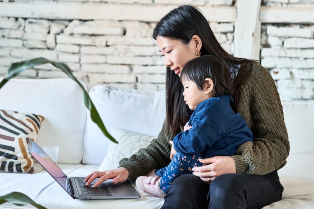 Mãe chinesa e bebê sorrindo na tela do laptop tempo alegre