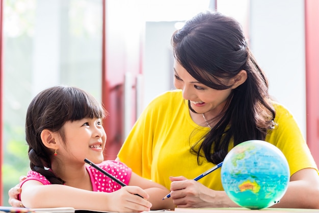 Mãe chinesa fazendo lição de casa de escola com criança