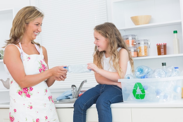 Mãe classificando resíduos de plásticos com sua filha