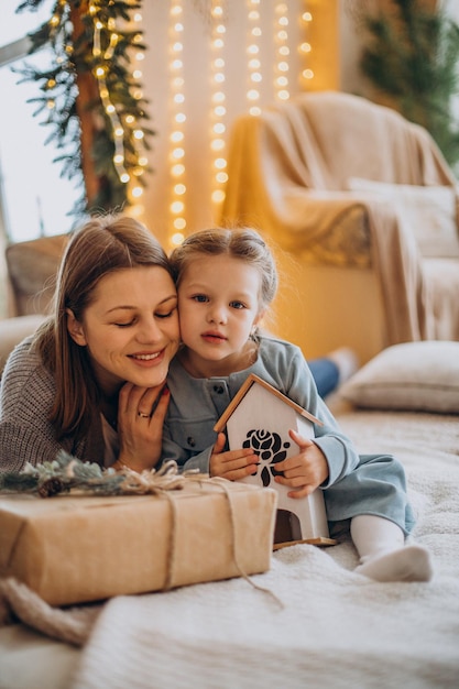 Mãe com a filha embalando presentes de natal e se divertindo