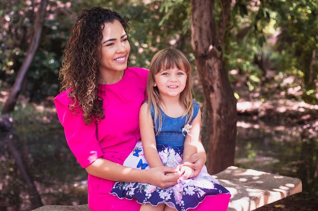 Mãe com a filha no colo no parque. Bela jovem mãe com a filha no parque. Dia das Mães