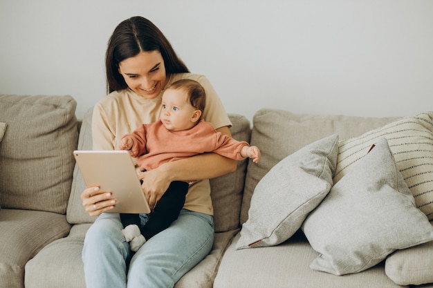 Mãe com a menina bbay usando o tablet em casa