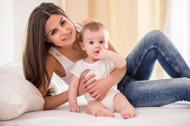 Mãe com bebê deitado na cama no quarto dela.