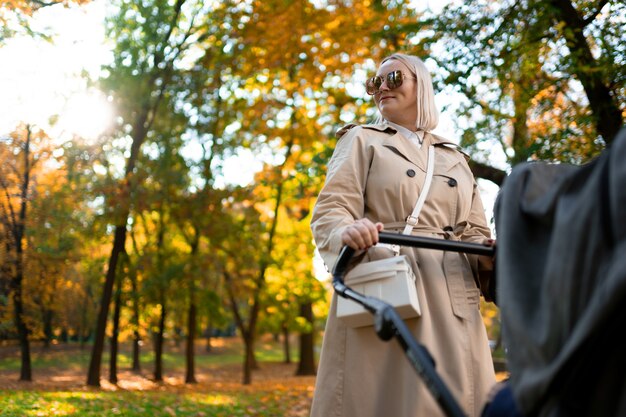 Mãe com carrinho de bebê caminhando no parque