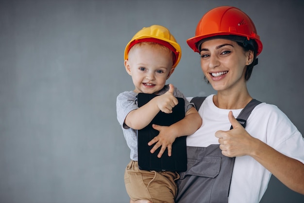 Foto mãe com construtores de menino usando capacetes laranja