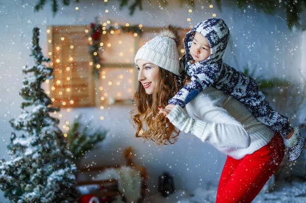 Mãe com criança no fundo da paisagem da casa do ano novo. Pessoas vestidas com roupas de inverno