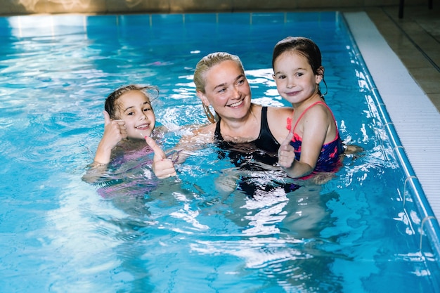 Mãe com duas filhas se divertindo na piscina coberta