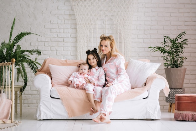 Foto mãe com duas filhas vestindo o mesmo pijama rosa