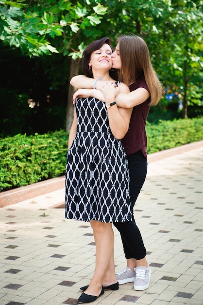 Mãe com filha adulta no parque junto.