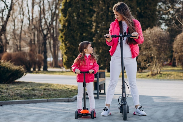 Mãe com filha andando de scooter elétrica