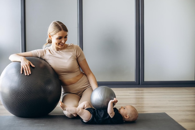 Mãe com filha bebê exercitando com bola de ioga