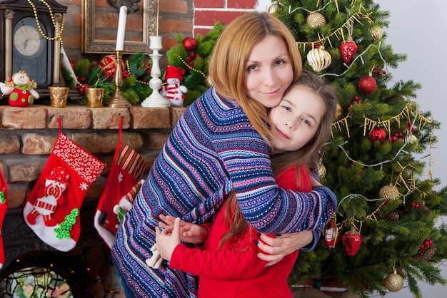 Mãe com filha com um presente perto da árvore de Natal