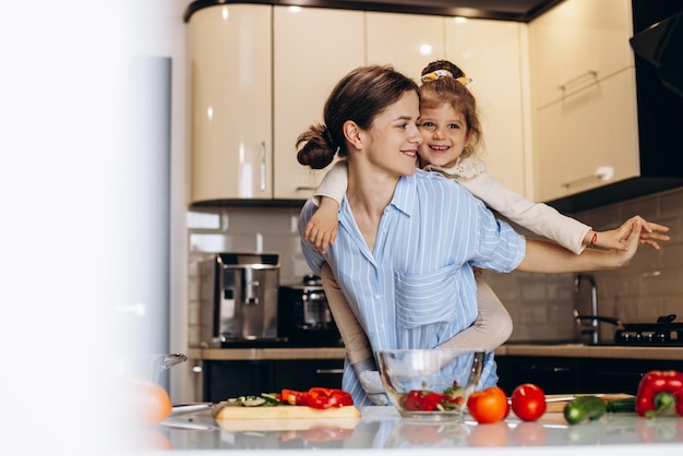 Mãe com filha cozinhando na cozinha e se divertindo