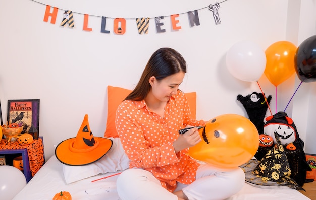 Mãe com filha fantasiada para comemorar o Halloween em casa. Criança com a mãe na decoração do quarto.