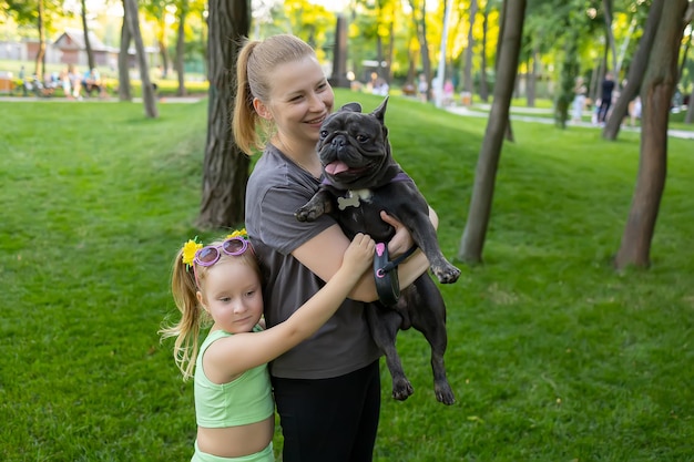 Mãe com filha no parque mãe segurando um buldogue francês em seus braços