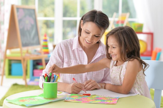 Mãe com filha pequena desenhando em casa