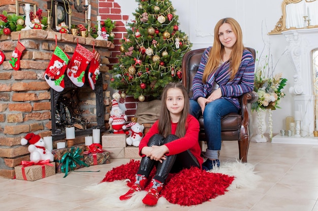 Mãe com filha perto da árvore de Natal