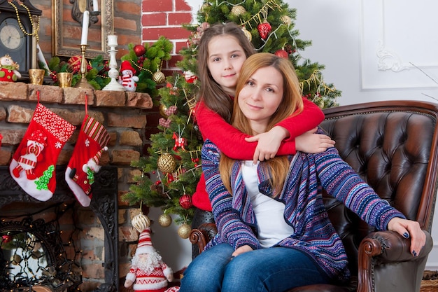 Mãe com filha perto da árvore de Natal