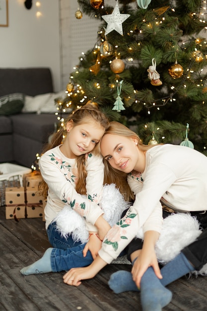 Mãe com filha perto da árvore de natal