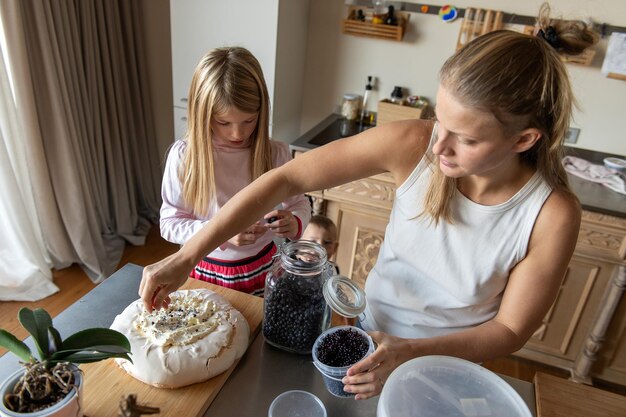 Mãe com filha preparando bolo de creme de sobremesa doce na cozinha da casa