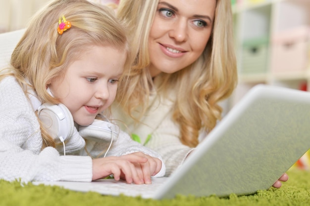 Mãe com filha usando laptop enquanto estava deitado no chão