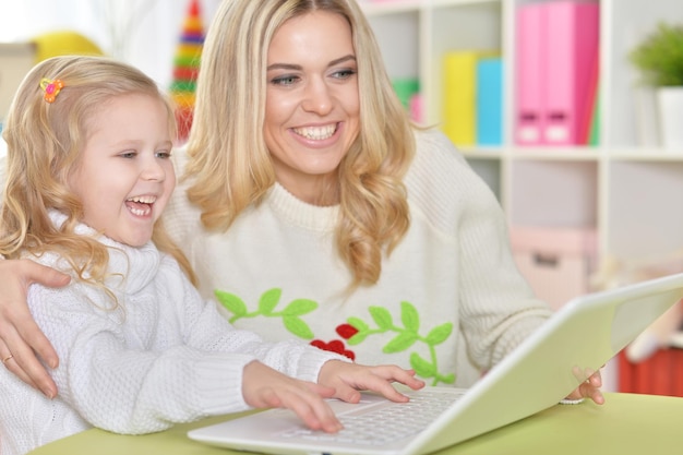 Mãe com filha usando laptop