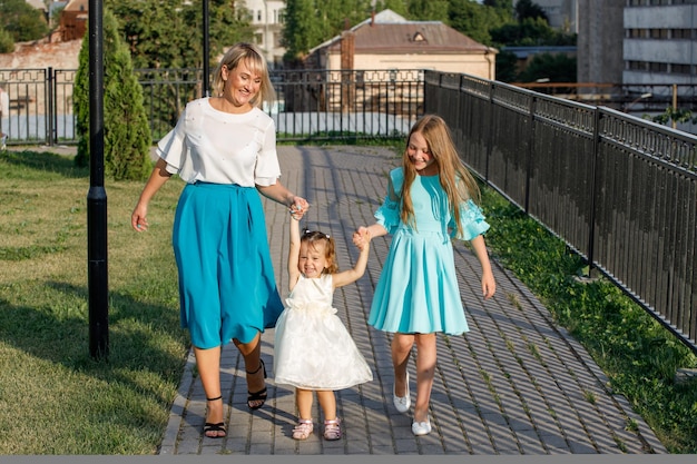 Mãe com filhas caminha no parque no verão. caminhada em família
