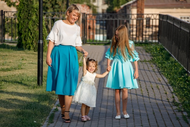Mãe com filhas caminha no parque no verão. caminhada em família