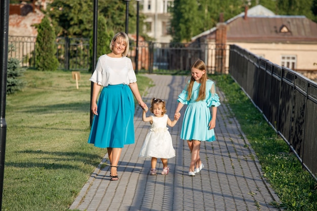 Mãe com filhas caminha no parque no verão. caminhada em família