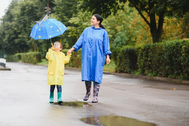 Mãe com filho caminhando na chuva sob o guarda-chuva