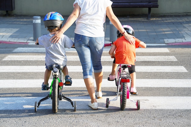 Foto mãe com filho e filha com uma bicicleta em uma zebra