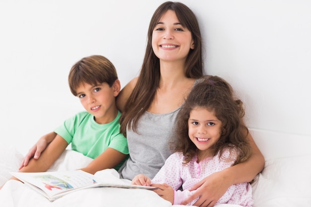 Mãe com filho e filha, livro de leitura