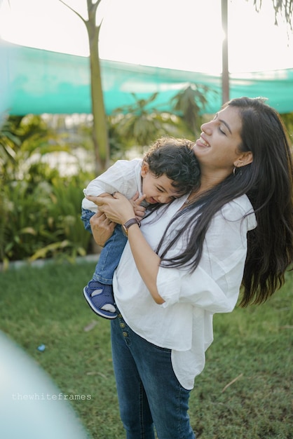 Mãe com filho filho brincando se divertindo juntos na grama em dia ensolarado de verão.