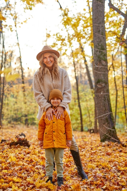 Mãe com filho na floresta de outono, retrato de família posando