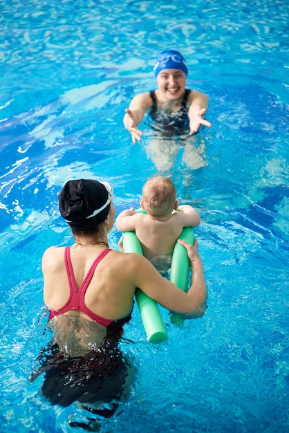 Mãe com filho na piscina Instrutor ensinando natação infantil Prevenção de doenças do sistema músculo-esquelético