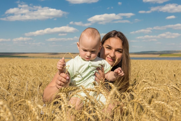 Mãe com filho no trigo Jovem família feliz no campo de trigo sorrindo e aproveitando o sol