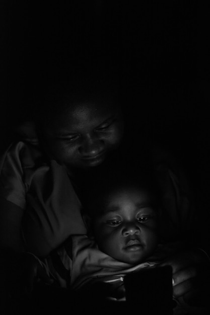 Mãe com filho usando telefone na sala escura