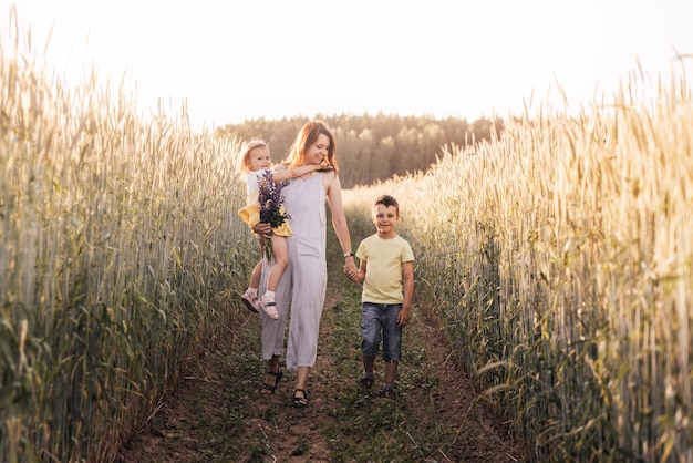 Mãe com filhos com seu filho e filha caminhando por um campo de trigo