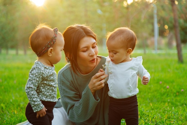 Mãe com filhos gêmeos soprando dente de leão